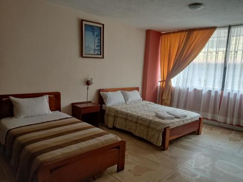 a hotel room with two beds and a window at Hotel Diana Real in Santo Domingo de los Colorados