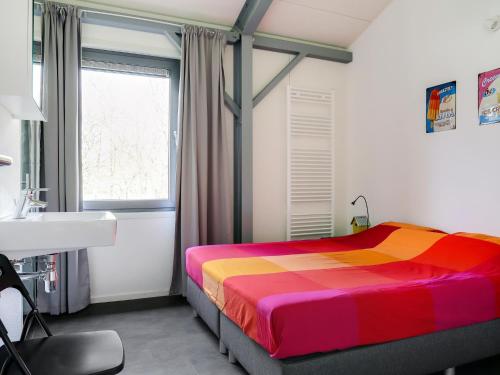 a bedroom with a colorful bed and a sink at Attractive holiday home in Noordwolde with sauna in Noordwolde