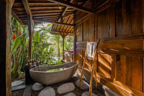 - une salle de bains avec baignoire dans un bâtiment en bois dans l'établissement Mandana Ubud Villa, à Ubud