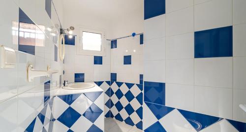 La salle de bains est pourvue de murs carrelés bleus et blancs et d'un lavabo. dans l'établissement Au coeur de l'arriere Pays Rez de chaussé de Villa DOMAINE A PRESA, à Sartène