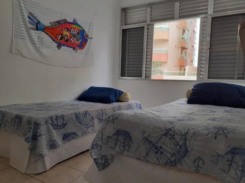 a room with two beds and a window at Good Vibes in Praia Grande