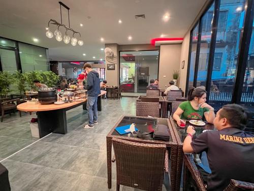 a group of people sitting at tables in a restaurant at The Harbour Front Hotel in Suratthani