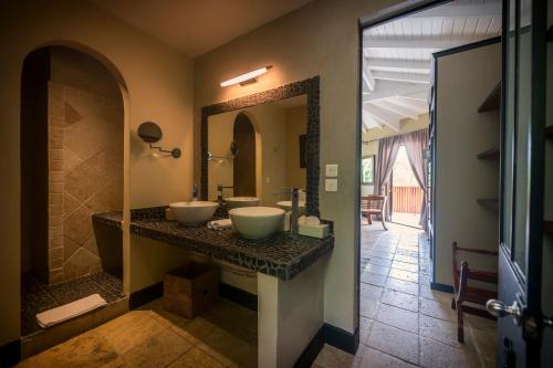 uma casa de banho com 2 lavatórios e um espelho grande em La Villa Hibiscus, Saint Martin em São Martinho