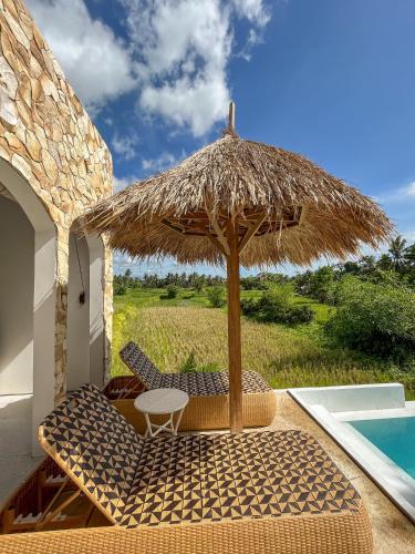 a table and chairs under a straw umbrella next to a swimming pool at Woywoy Escape Samu (Adults Only) in Ubud