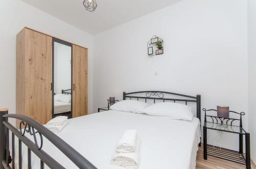 a bedroom with a large white bed with a mirror at Apartments Marina in Postira