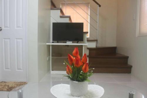 un jarrón con flores rojas sobre una mesa en la sala de estar en Pontefino Prime Townhouse 4BR with Wifi & Pool en Batangas