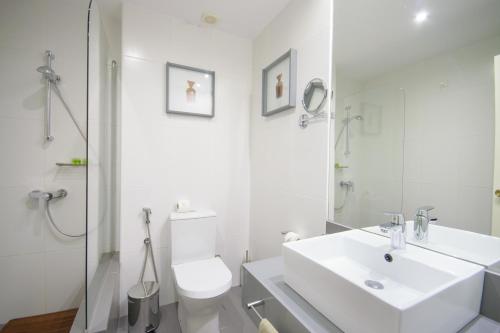 a white bathroom with a toilet and a sink at Oasis Porto Grande in Mindelo