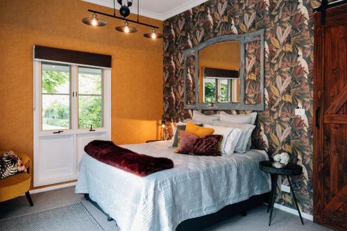 a bedroom with a bed with a mirror on the wall at Chanticleer Gardens Barn cottage with a Pool in Dural