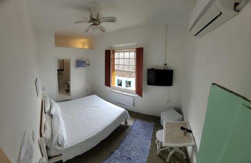 a white bedroom with a bed and a window at Pousada Casa Da Lapa in Paraty