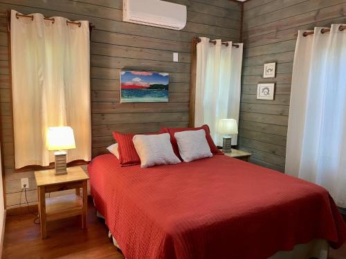 Phoenix House في Sandy Bay: غرفة نوم بسرير احمر مع مصباحين