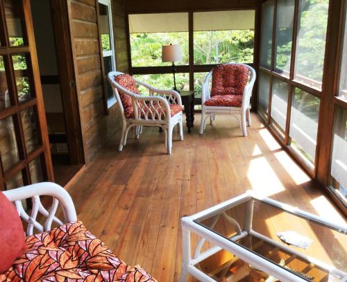 a screened in porch with two chairs and a table at Phoenix House in Sandy Bay