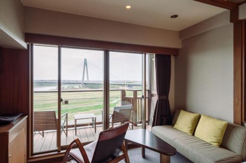 a room with a couch and a table and a balcony at Tokachigawa Onsen Daiichi Hotel in Otofuke