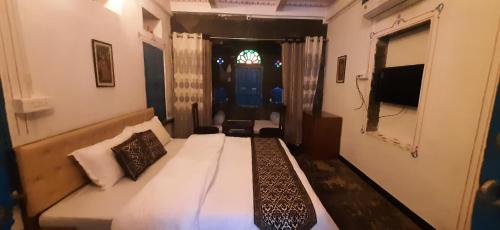 a bedroom with a bed and a window and a tv at Madan Mohan Villas (A Haritage Haveli Home Stay) in Udaipur