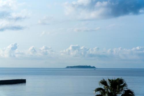 an island in the ocean with a palm tree in the foreground at Pearl Star Hotel ATAMI in Atami
