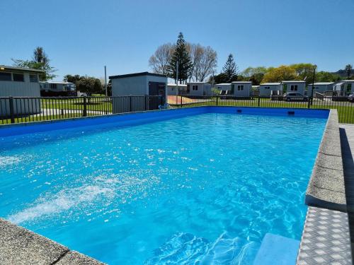 a swimming pool with blue water in a yard at Whakatane Holiday Park in Whakatane