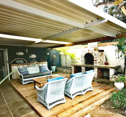 a patio with wicker chairs and a table and a fireplace at Sky Tyde's Beach House in Port Shepstone