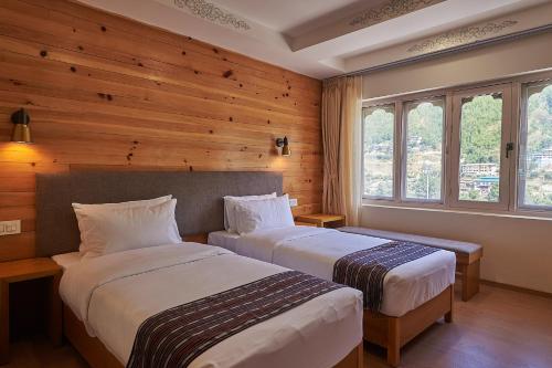 Duas camas num quarto com paredes e janelas de madeira em The Willows Hotel, Bhutan em Thimphu