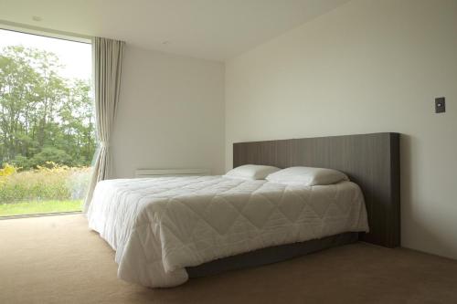 een slaapkamer met een bed en een groot raam bij Furano Peak in Furano