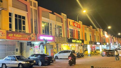 Chempaka Kluang Homestay في كلوانج: شارع المدينة مزدحم ليلاً مع وقوف السيارات