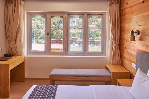 a bedroom with a window and a bed and a desk at The Willows Hotel, Bhutan in Thimphu