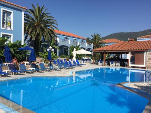 a large swimming pool with chairs and a hotel at Blue Sky Hotel - Petra - Lesvos - Greece in Petra
