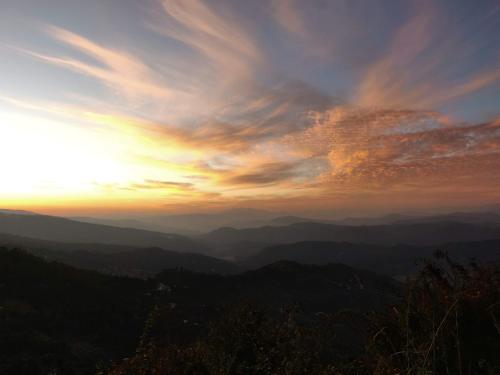 a sunset in the mountains with the sun setting at Meraki - Entire 2BHK Villa With Himalayan Views in Rānīkhet