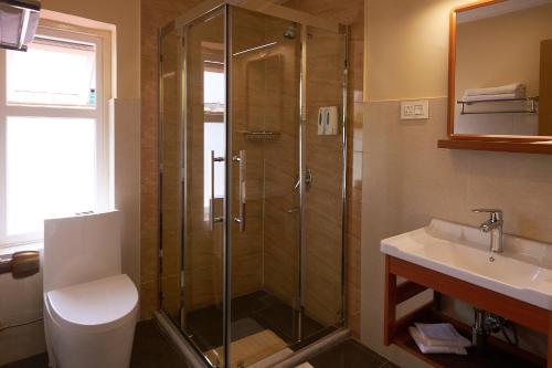 ein Bad mit einer Dusche, einem WC und einem Waschbecken in der Unterkunft The Willows Hotel, Bhutan in Thimphu