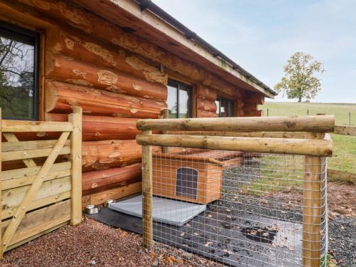 a log cabin with a chicken cage in front of it at Cedar Cabin in Worcester