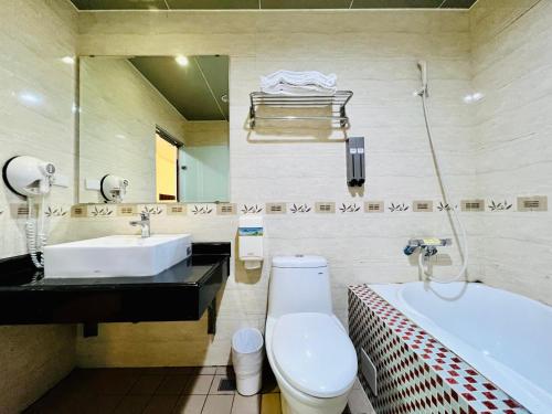 a bathroom with a toilet and a sink and a tub at Mucha Boutique Hotel in Yilan City