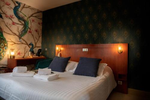 a bedroom with a large bed with blue pillows at Logis Hôtel Restaurant La Breche in Amboise