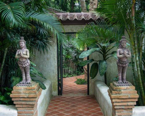 a gate to a garden with two statues oficans at Baanpong Lodge in San Kamphaeng