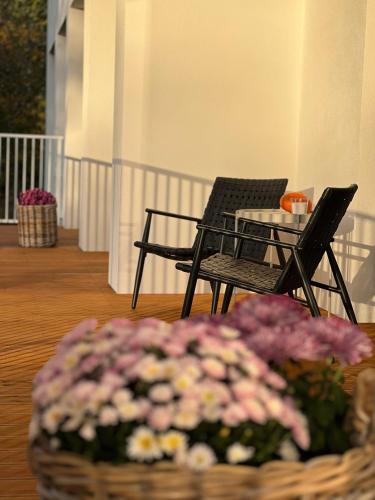 two chairs and a table with flowers on a porch at Apartamenty HELIOS in Jastrzębia Góra