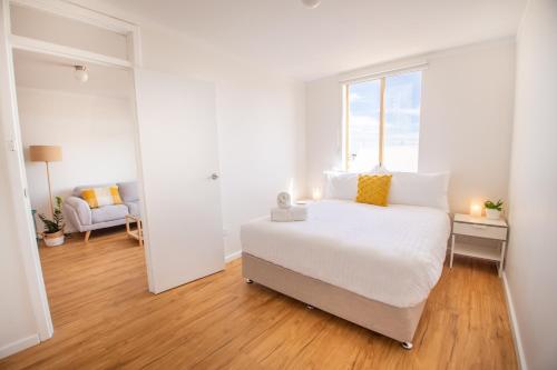 a white bedroom with a large bed and a window at Central Fremantle Lifestyle Walk To Markets & Cafe in Fremantle