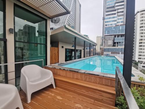 a balcony with a swimming pool and a white chair at Tints of Blue Hotel in Bangkok