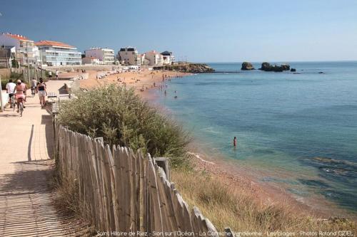a beach with people swimming in the water and a fence at GÎTE DE L'ODA in Le Poiré-sur-Vie