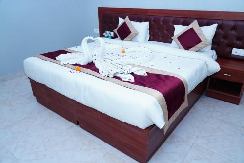um quarto com uma cama grande e toalhas brancas em ExpoMart Inn em Greater Noida