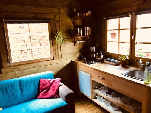 a kitchen with a blue couch and a sink at Tiny House Andersom Anders in Bad-Nieuweschans