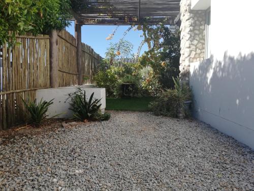 einen Hinterhof mit einem Zaun und einer Kiesterrasse in der Unterkunft Sailors cottage in Paternoster