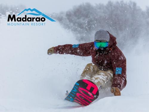 a man riding a snowboard down a snow covered slope at Madarao Kogen Hotel in Iiyama