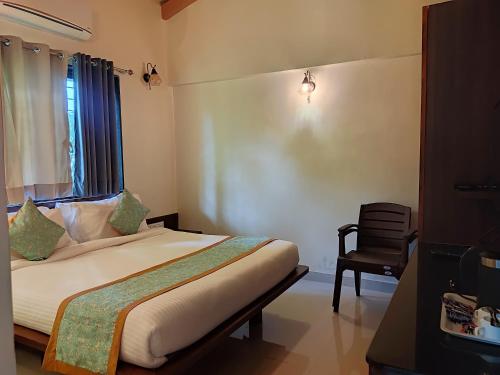 a bedroom with a bed with a window and a chair at Cocorico Beach Resort in Dapoli