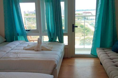 two beds in a room with blue curtains and windows at Relaxing Stay with Sea View at Arterra in Mactan