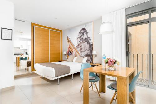 Habitación de hotel con cama, mesa y sillas en Suites Del Pintor, en Málaga