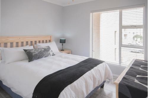 a bedroom with a large bed and a window at Big Bay Beach Club 134 in Bloubergstrand