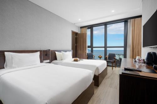 a hotel room with two beds and a desk at Emerald Bay Hotel & Spa Nha Trang in Nha Trang