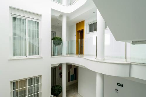 an internal view of a white building with a spiral staircase at Suites Del Pintor in Málaga