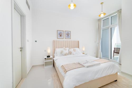 - une chambre blanche avec un grand lit et une fenêtre dans l'établissement Immaculate 1BR apartment at Carson C, à Dubaï