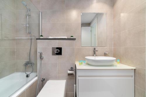 y baño con lavabo, ducha y bañera. en Immaculate 1BR apartment at Carson C, en Dubái