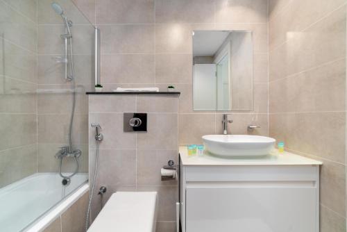 a bathroom with a sink and a shower and a tub at Immaculate 1BR apartment at Carson C in Dubai