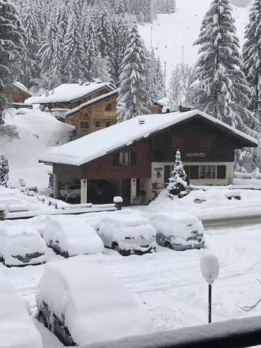 una casa cubierta de nieve con coches aparcados delante en La montagne « un coin d’oxygène » en Châtel