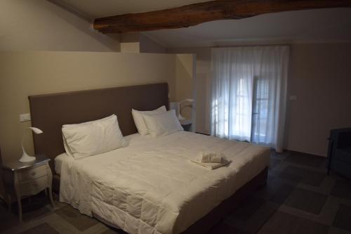 a bedroom with a large bed with white sheets and a window at Villa cantoni marca superior in Sabbioneta
